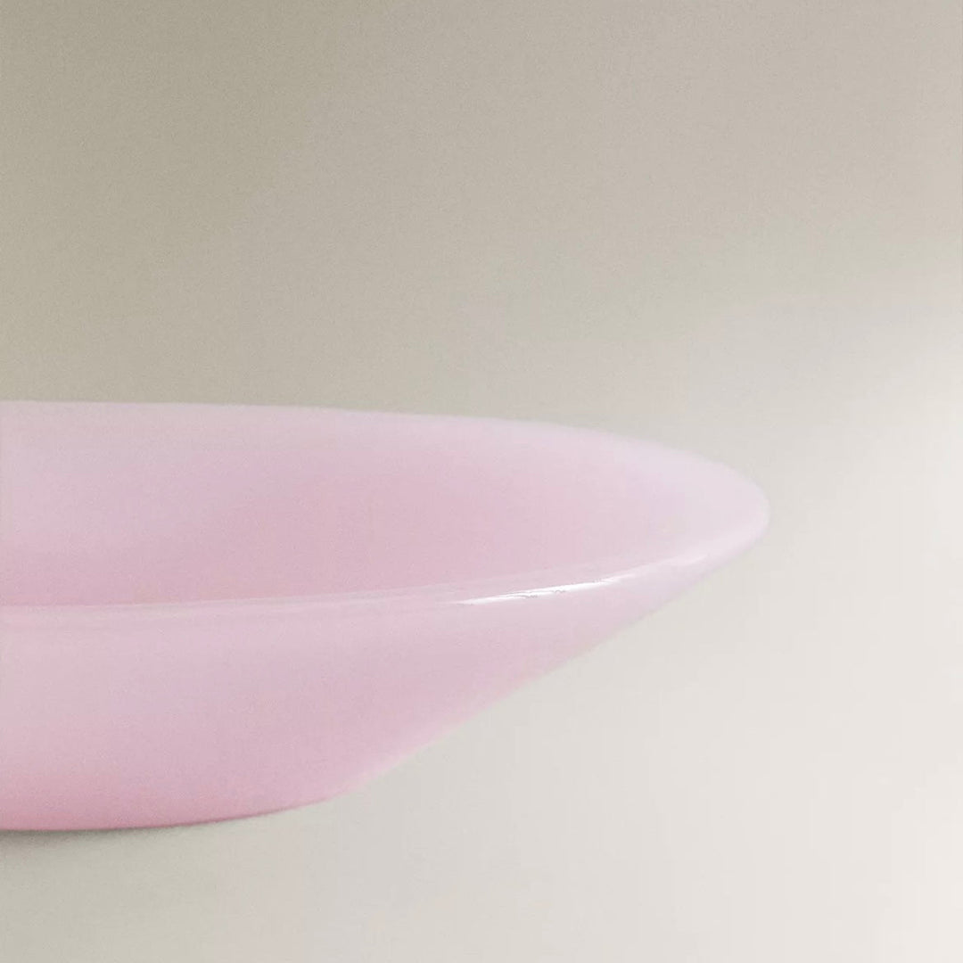 Pink glass bowl by Nanushka with a glossy finish and curved shape.
