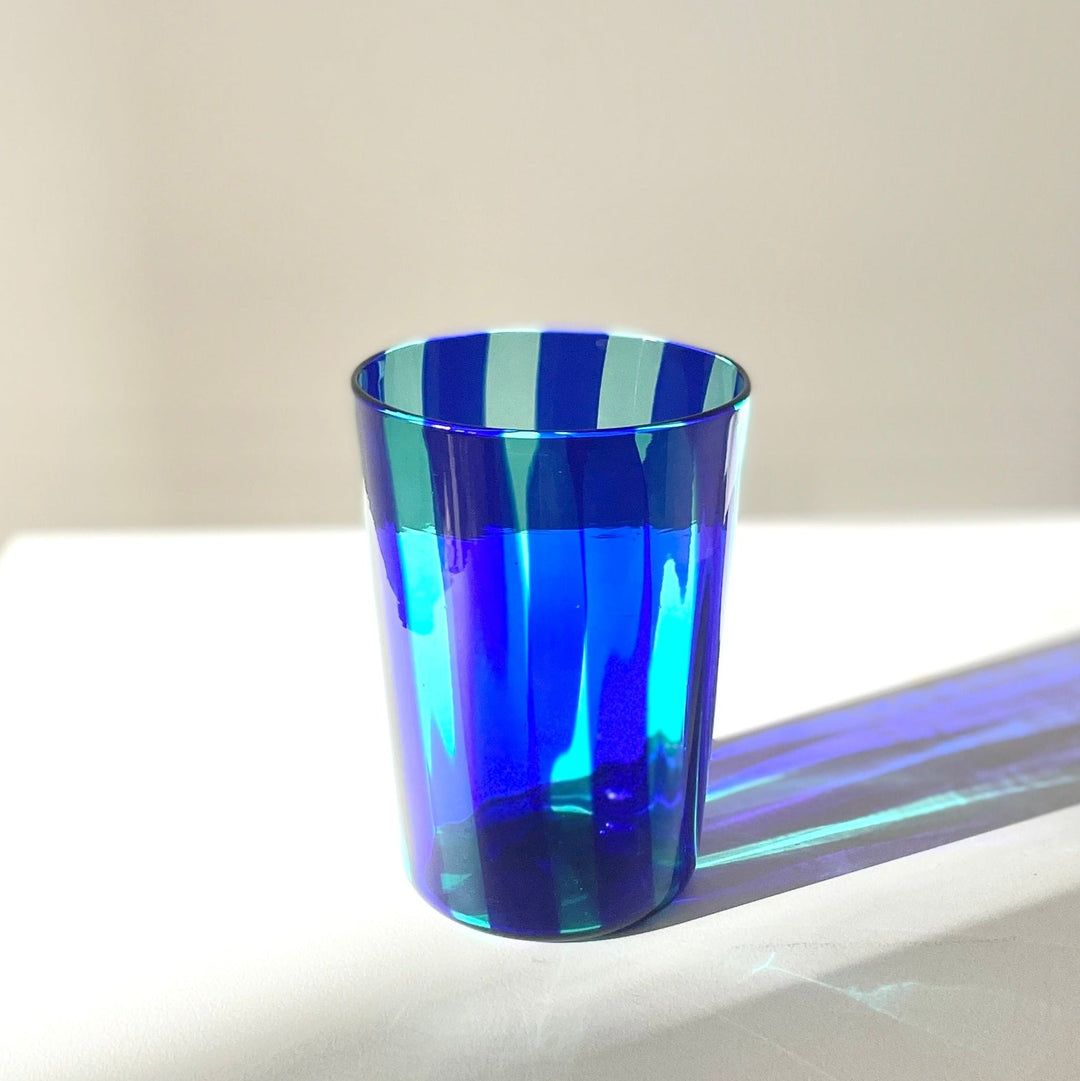 A blue tumbler with white stripes from the 'Berlingot Evo' collection, handmade in Murano, Venice.