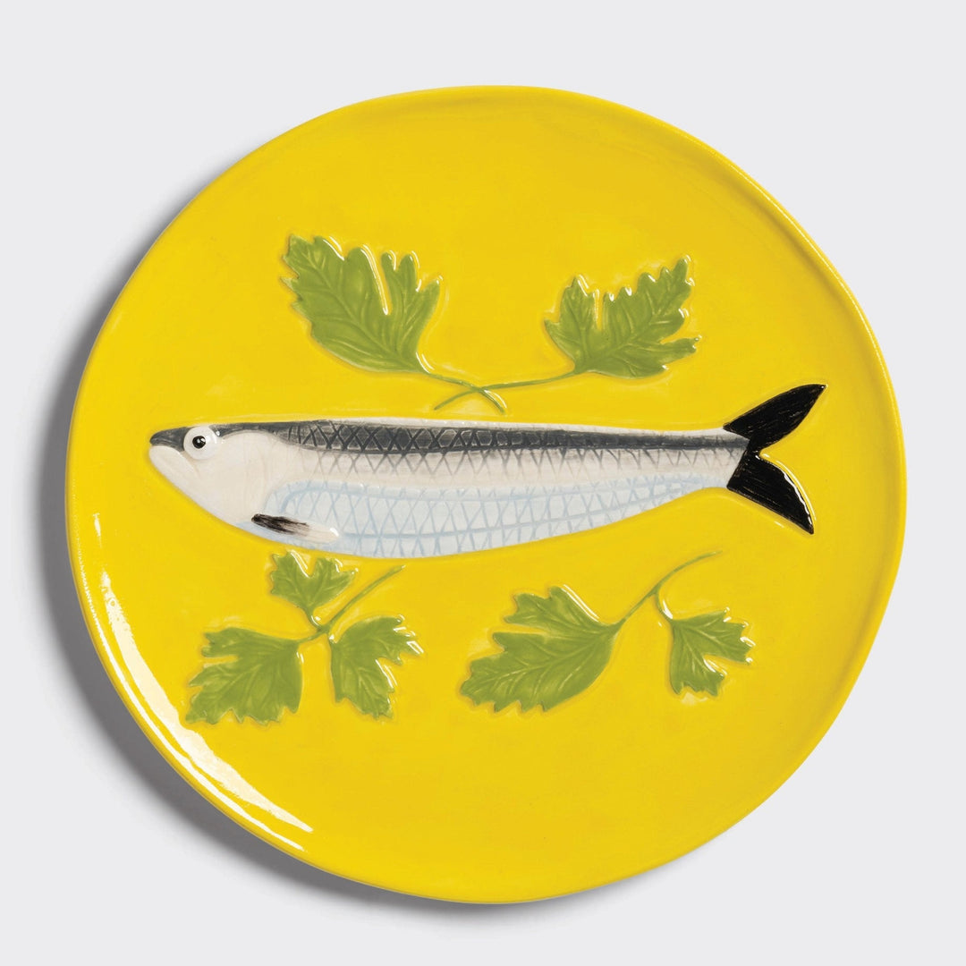 Yellow decorative plate by &Klevering with a fish and parsley design.