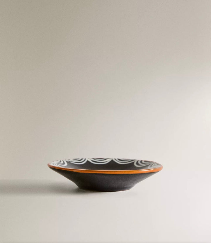 Painted earthware side plate by Nanushka with decorative white wave pattern around the rim.