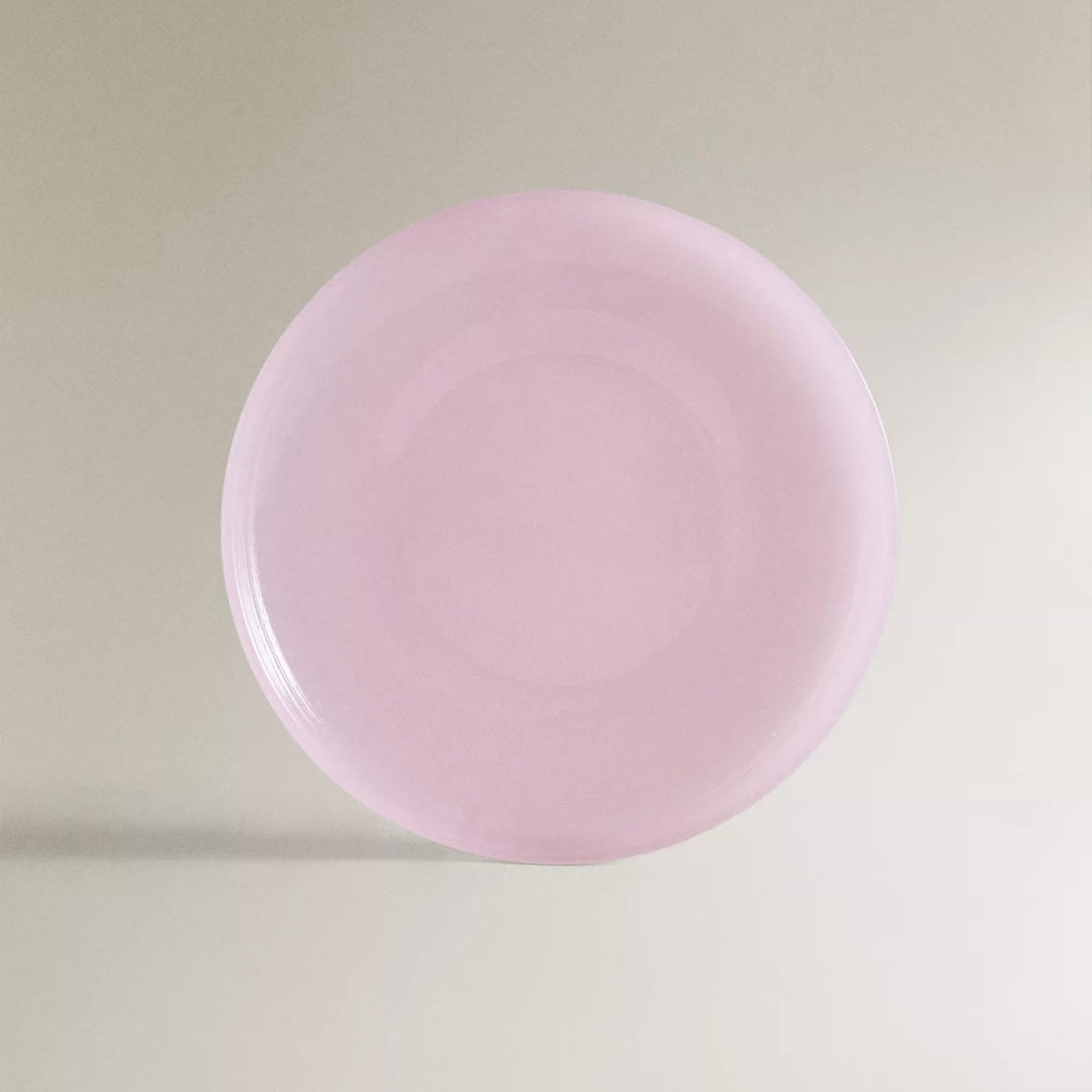 A translucent pink glass dinner plate with a textured effect.