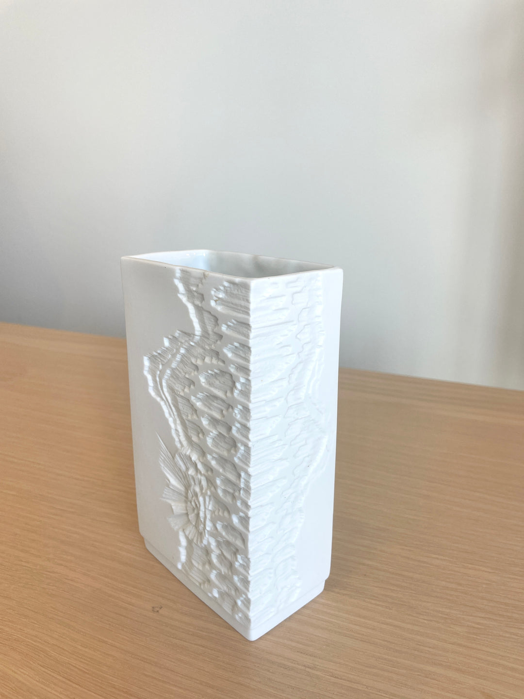 White porcelain vase by Kaiser with a raised floral design on the side.