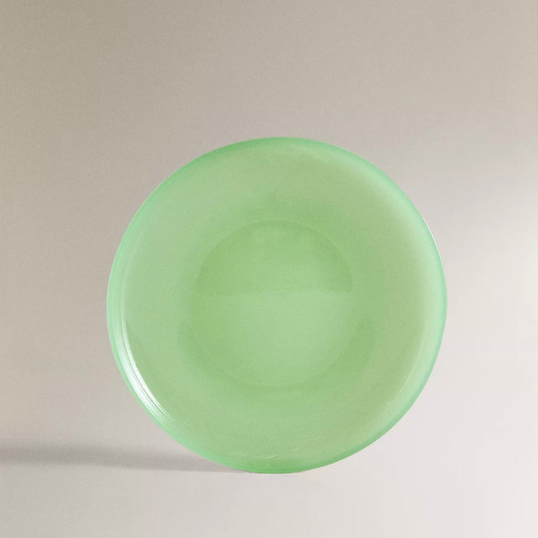 A round green glass dinner plate with a translucent effect.