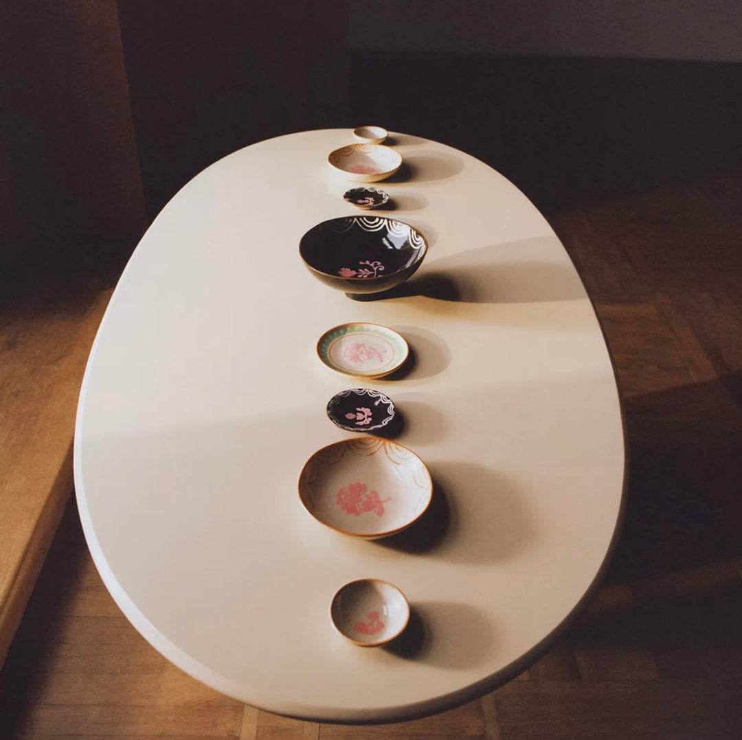 Painted earthware mini bowl by Nanushka with a pink floral design, arranged on a cream table.