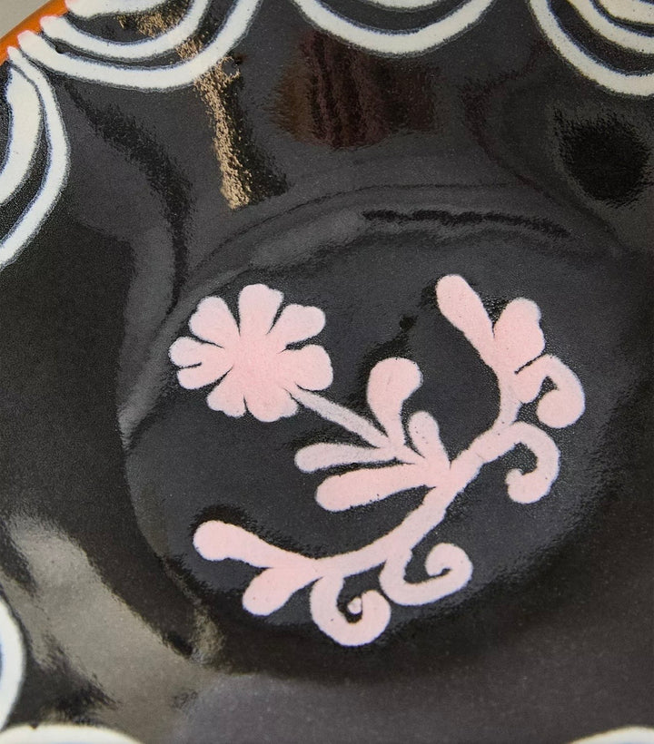 Painted earthware side plate from Nanushka, decorated with a floral pattern in light pink.