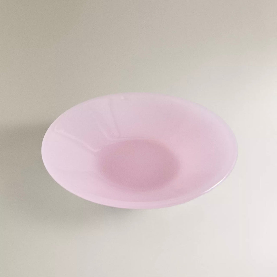 A translucent pink coloured glass bowl with a textured effect, displayed against a neutral background.
