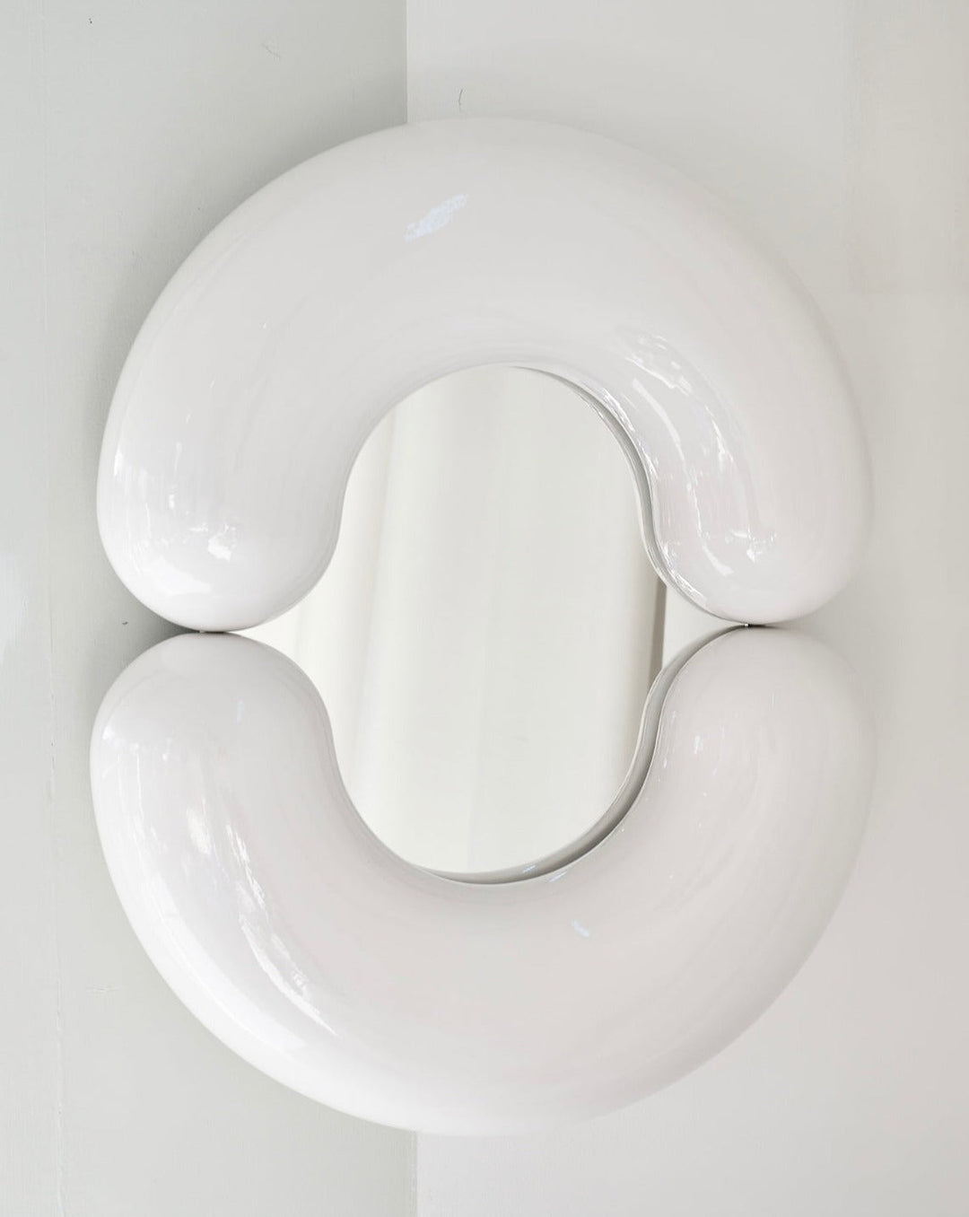 White wall mirror by Moustache Paris with a rounded, sculptural shape.