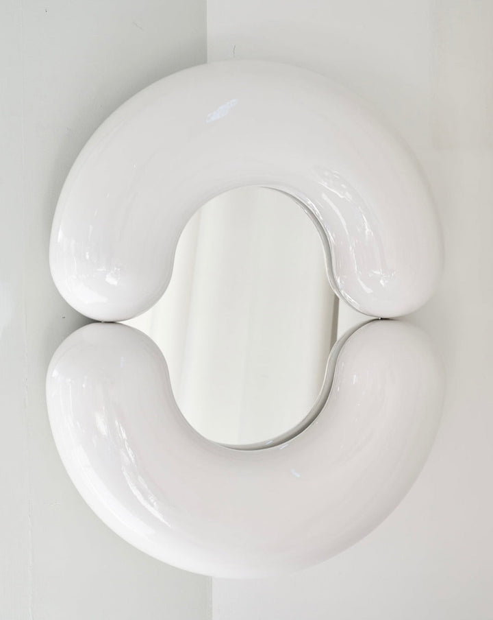 White wall mirror by Moustache Paris with a rounded, sculptural shape.