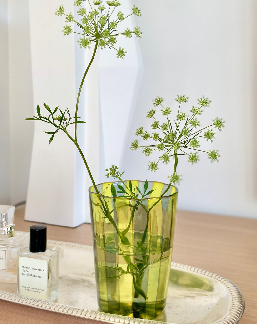 Yellow and steel drinking glass tumbler by LAGUNA-B, decorated with a floral arrangement on a silver tray.
