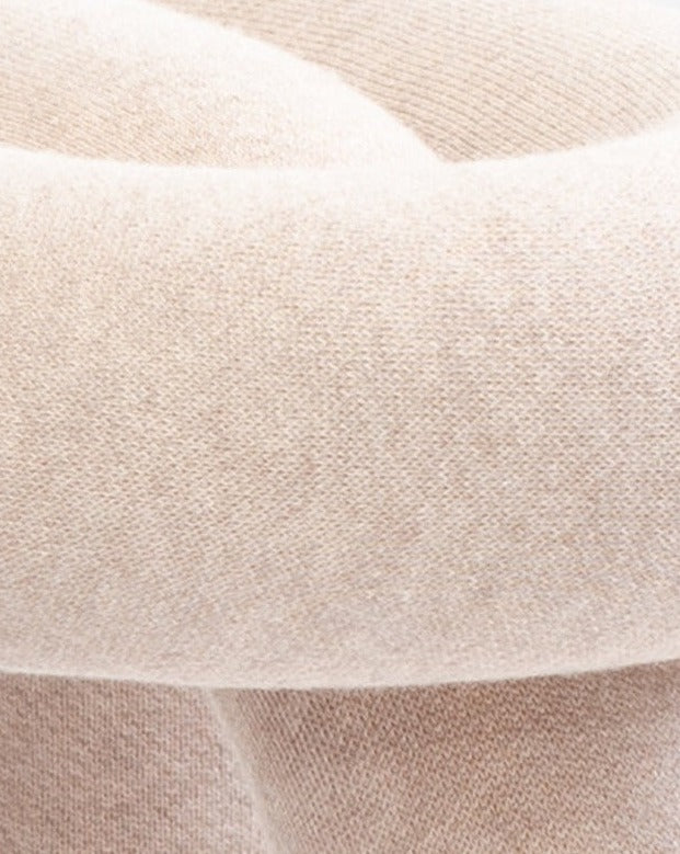 Cropped view of a beige knitted stool with a soft, textured surface.