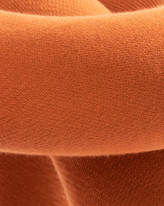 Cropped close-up of an orange fabric stool with visible textile texture.