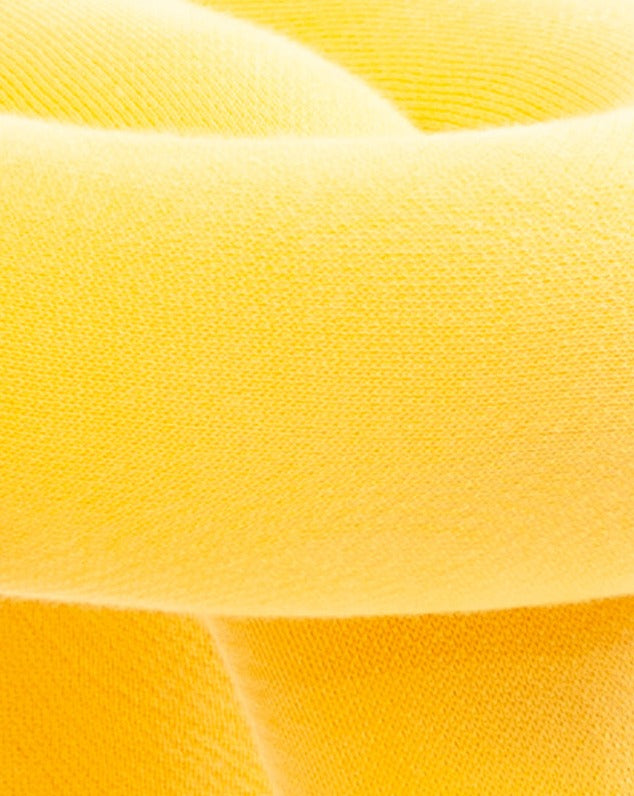 Yellow fabric stool with a soft, textured surface.