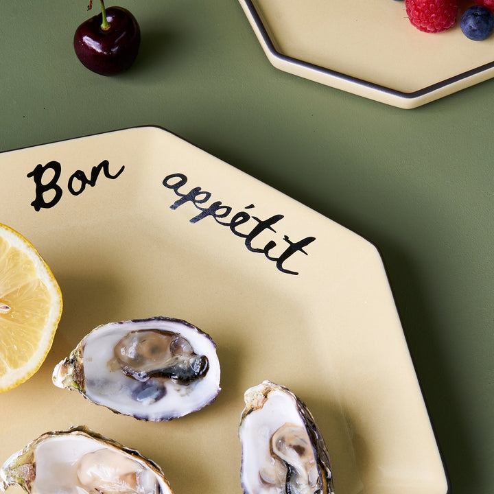 Wheat Black Blaze Gem Dinner Plate with "Bon Appetit" written on it, oysters, and a lemon.