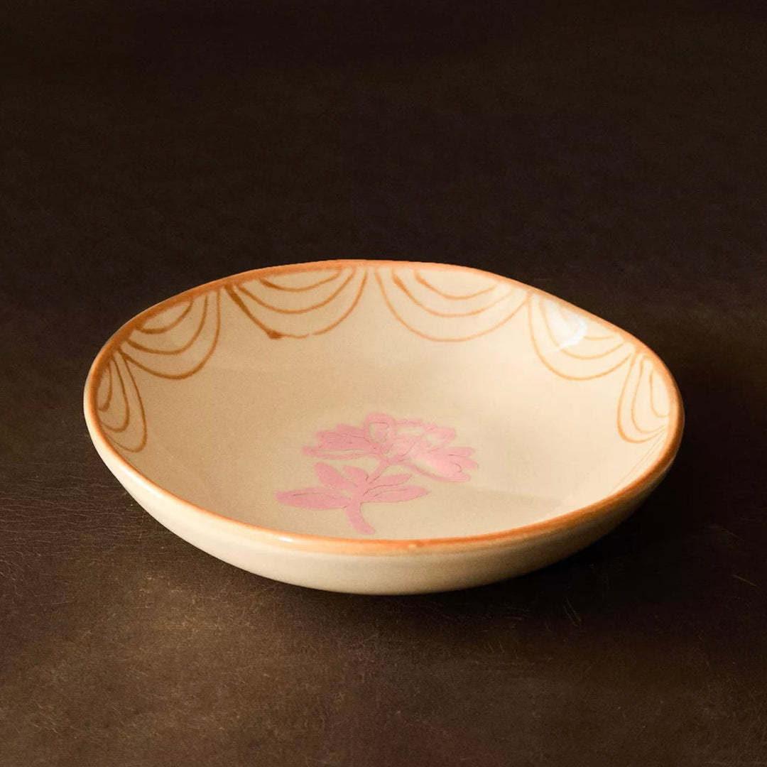 Earthware salad bowl by Nanushka, featuring painted pink flower and scalloped rim design.
