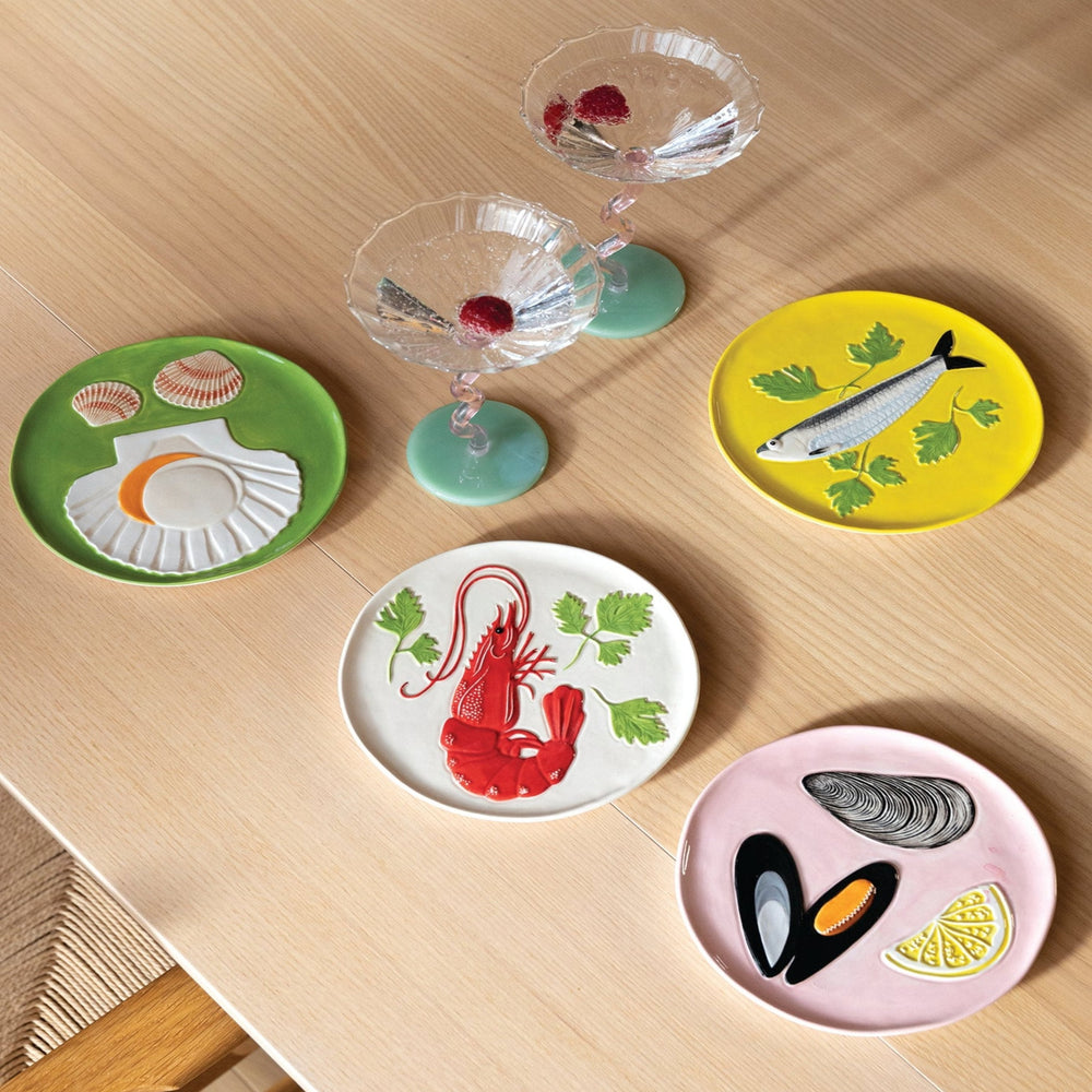 Set of four plates de la mer by &Klevering, featuring a green scallop, yellow sardine, white prawn and pink mussel design.