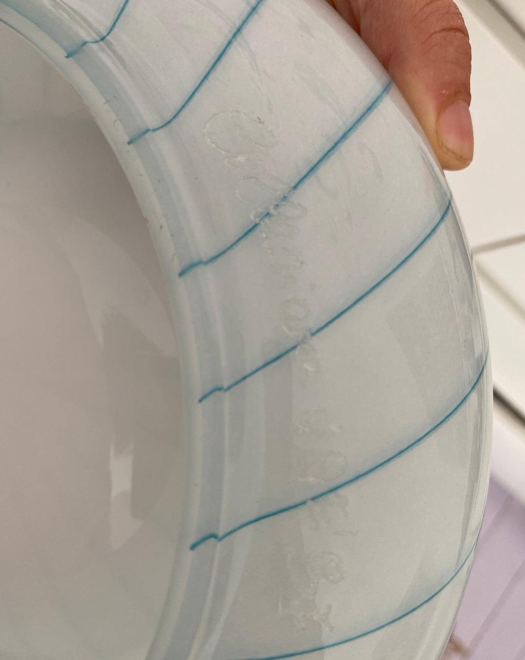 White glass decorative bowl with blue stripes, signed from the 1960s, featuring a rounded shape and smooth texture.