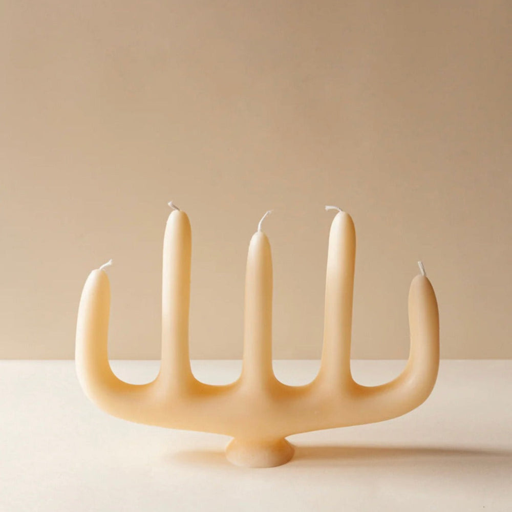 Beige candelabra candle by Anthropologie, shaped like a five-pronged holder with short, lit candles.