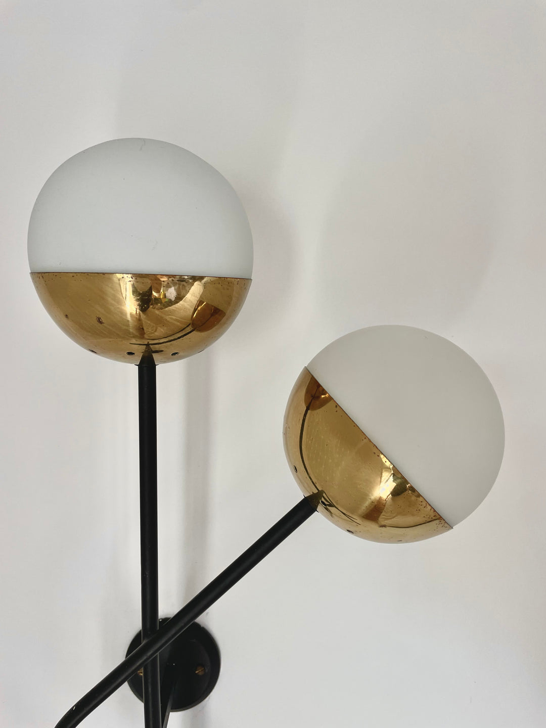 Pair of vintage brass wall lights by Stilnovo, featuring a spherical shade and black metal rods.