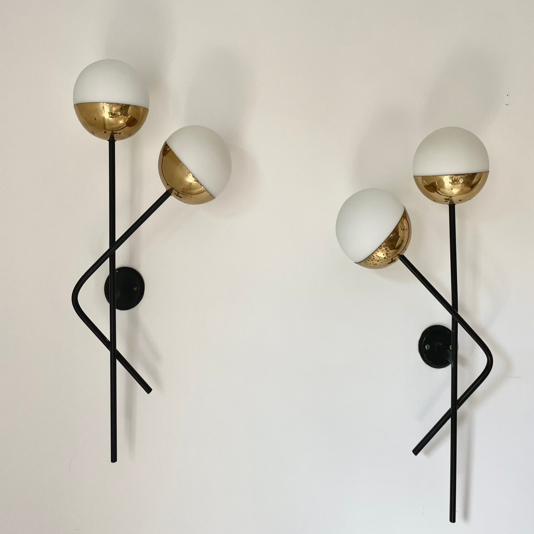 A pair of Stilnovo wall lights with brass and painted metal accents and opal glass diffusers, mounted on a wall.