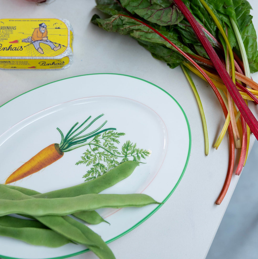 Ceramic carrot serving plate by &Klevering, with green beans and colorful chard as garnish.
