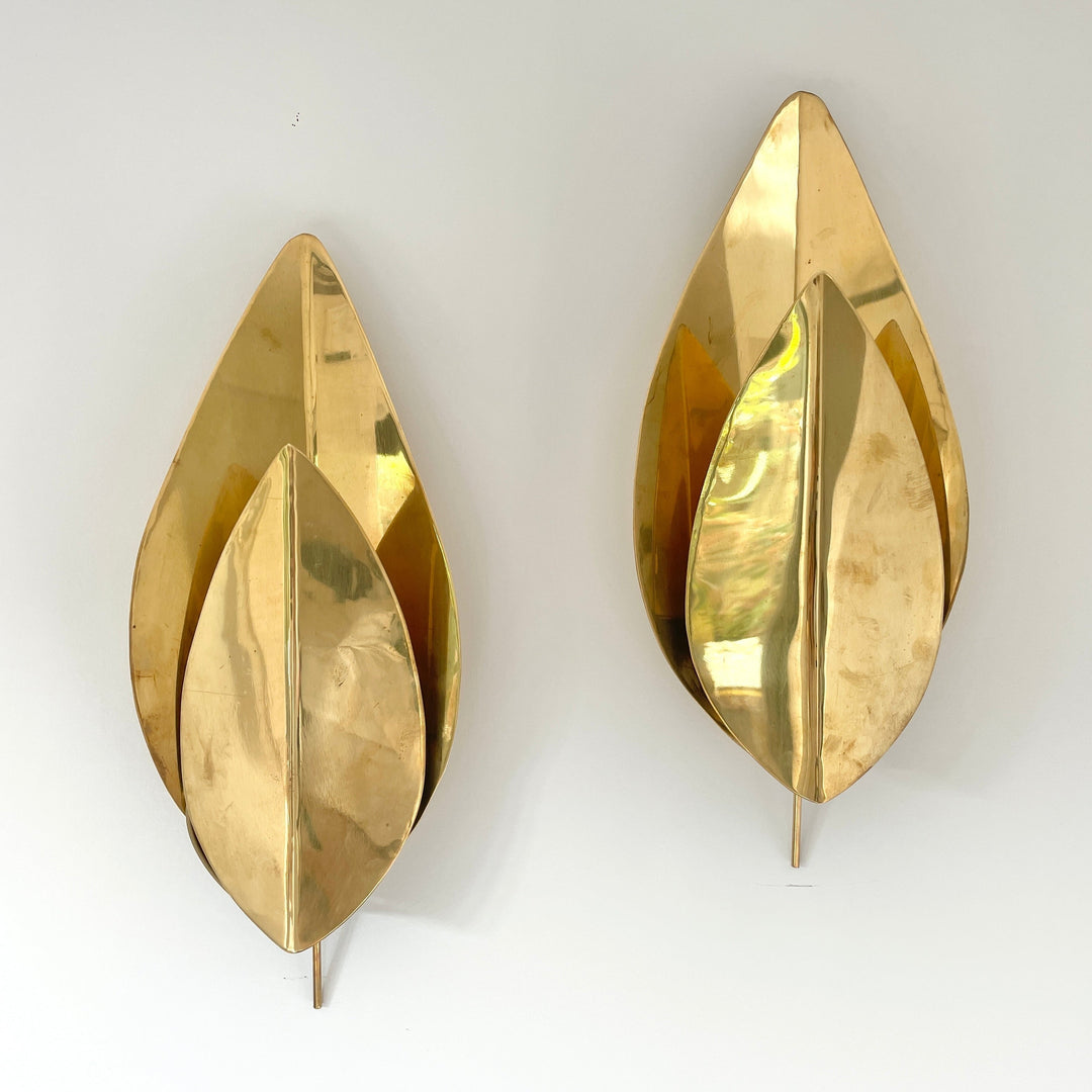 Gold tone vintage wall lights by Tommaso Barbi, with layered petal-like leaves against a white wall.