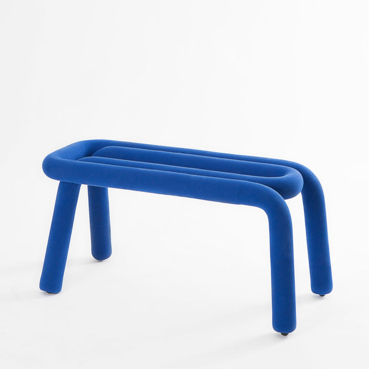 Blue upholstered bench by Moustache with three curved horizontal sections and matching rounded legs.