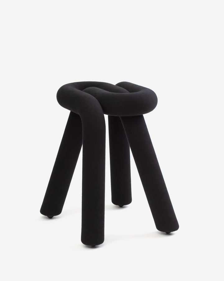 Black stool with knot design by Moustache, featuring a soft texture and three legs with small wheels.