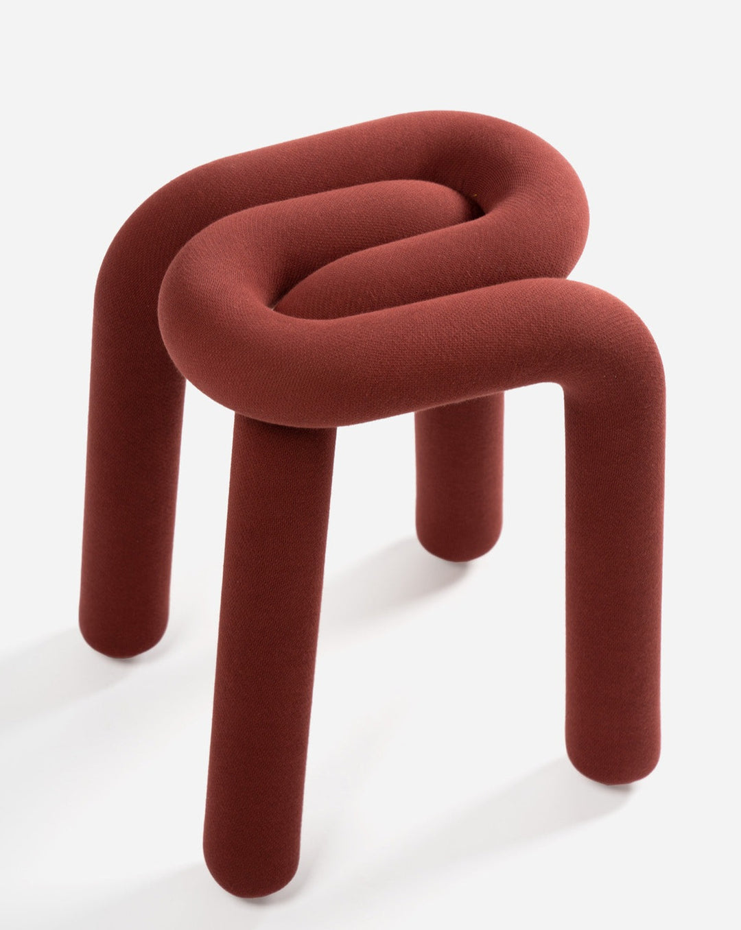 Upholstered red stool by Moustache featuring a looped design and three cylindrical legs.