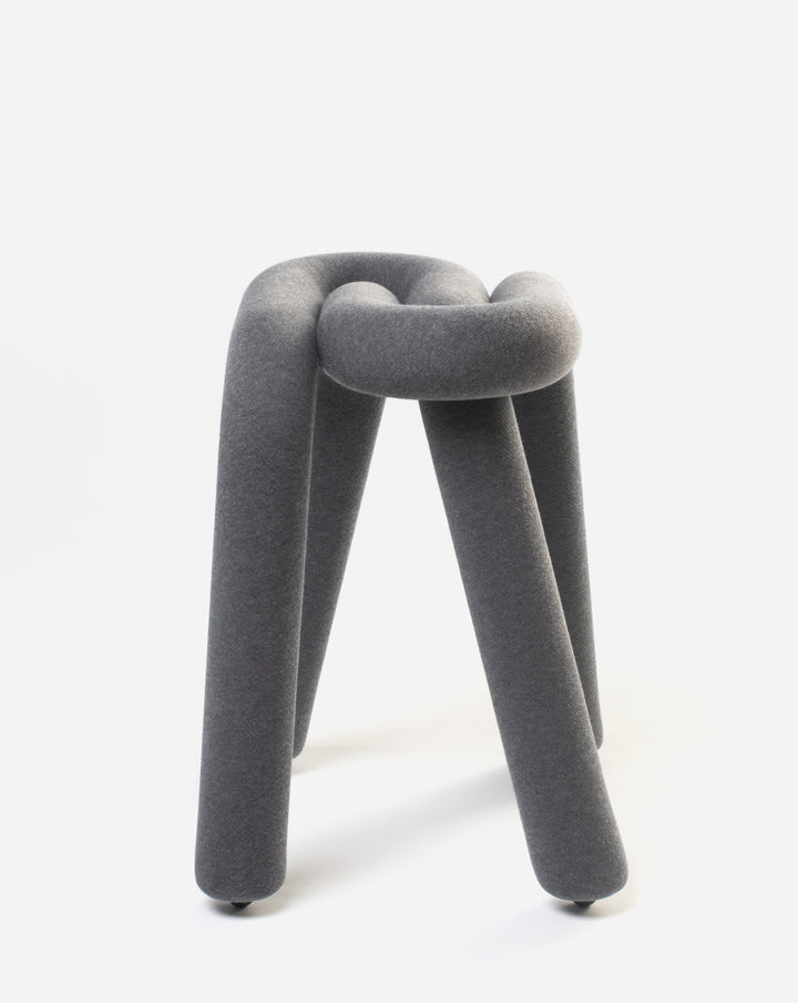 Grey fabric stool by Moustache, with an intertwined tubular design and short cylindrical legs.