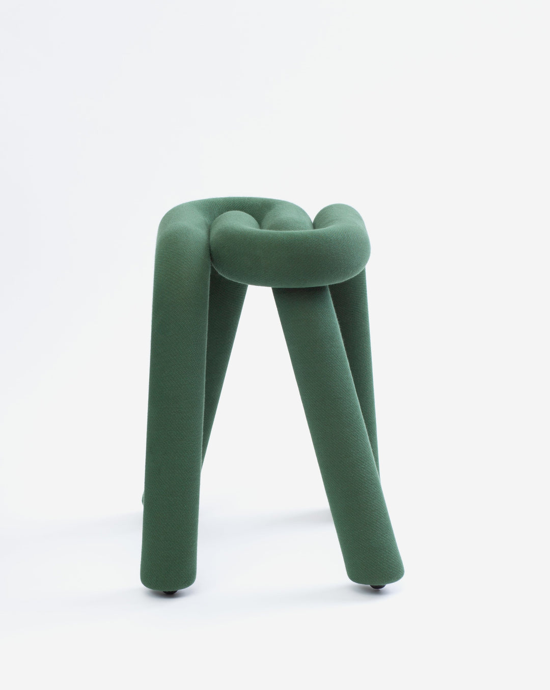 Green fabric stool by Moustache, featuring a knotted design and round feet, against a white background.