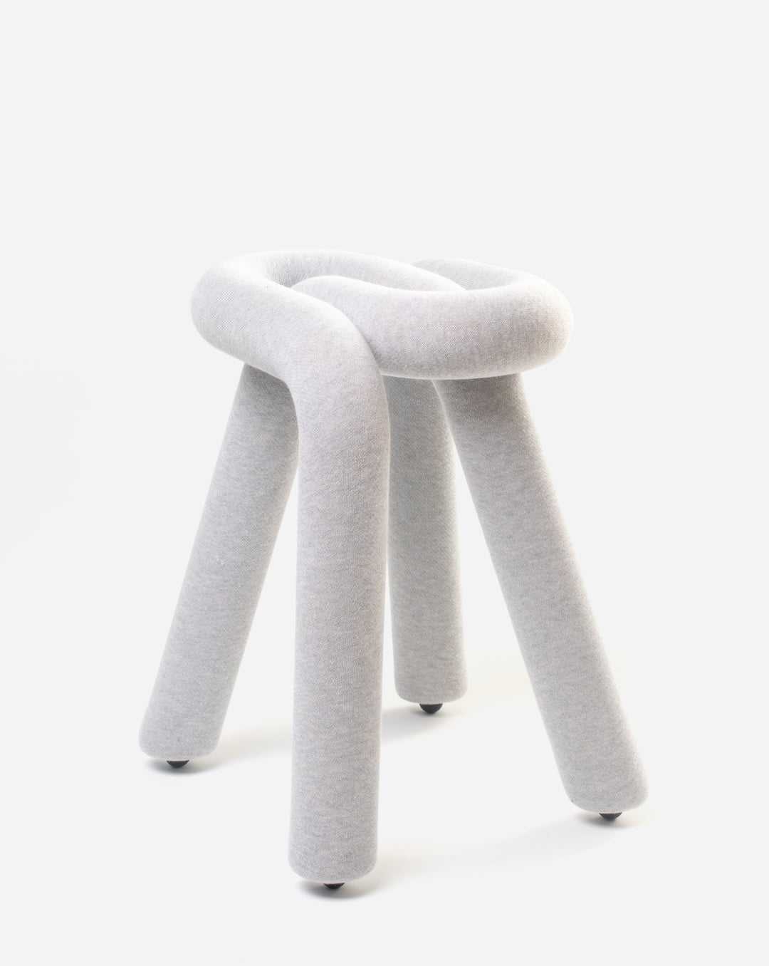 Gray fabric stool by Moustache, featuring a knotted top and cylindrical legs with dark footings, against a white background.