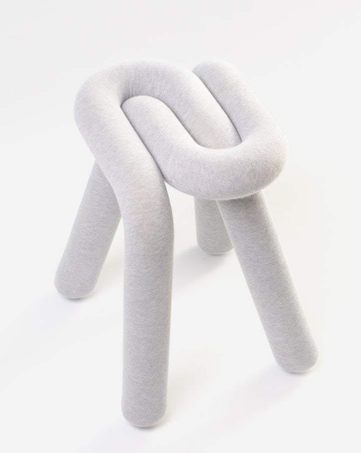 Gray upholstered stool by Moustache with a knot-like design and rounded legs, shown against a white background.