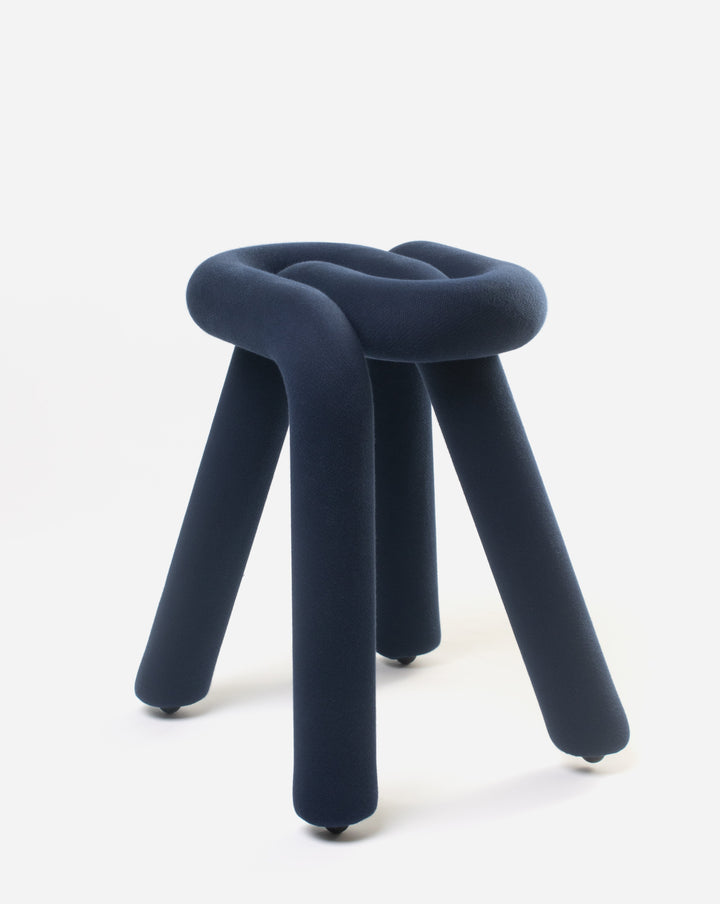 Purple stool by Moustache, featuring a soft, knotted design with four cylindrical legs and small rolling casters.