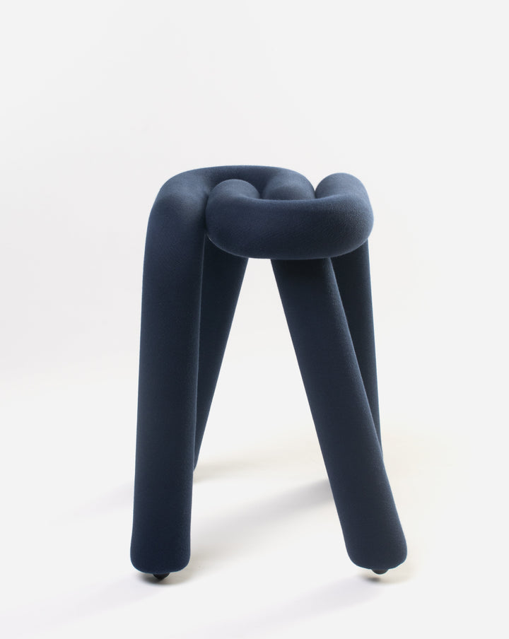 Purple knotted stool by Moustache with dark fabric covering, standing on three legs with casters.
