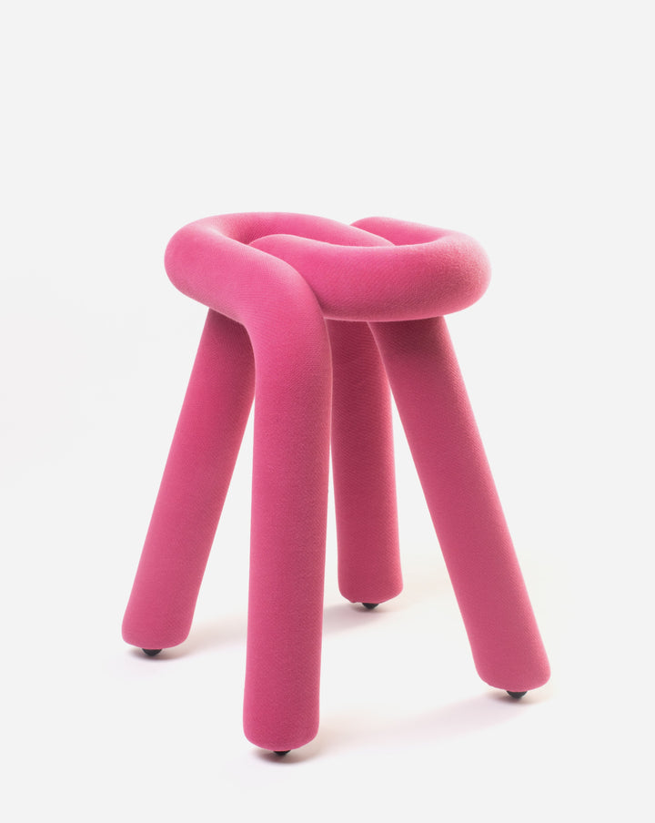 Pink padded stool from Moustache, with a knotted seat and three cylindrical legs on small casters.