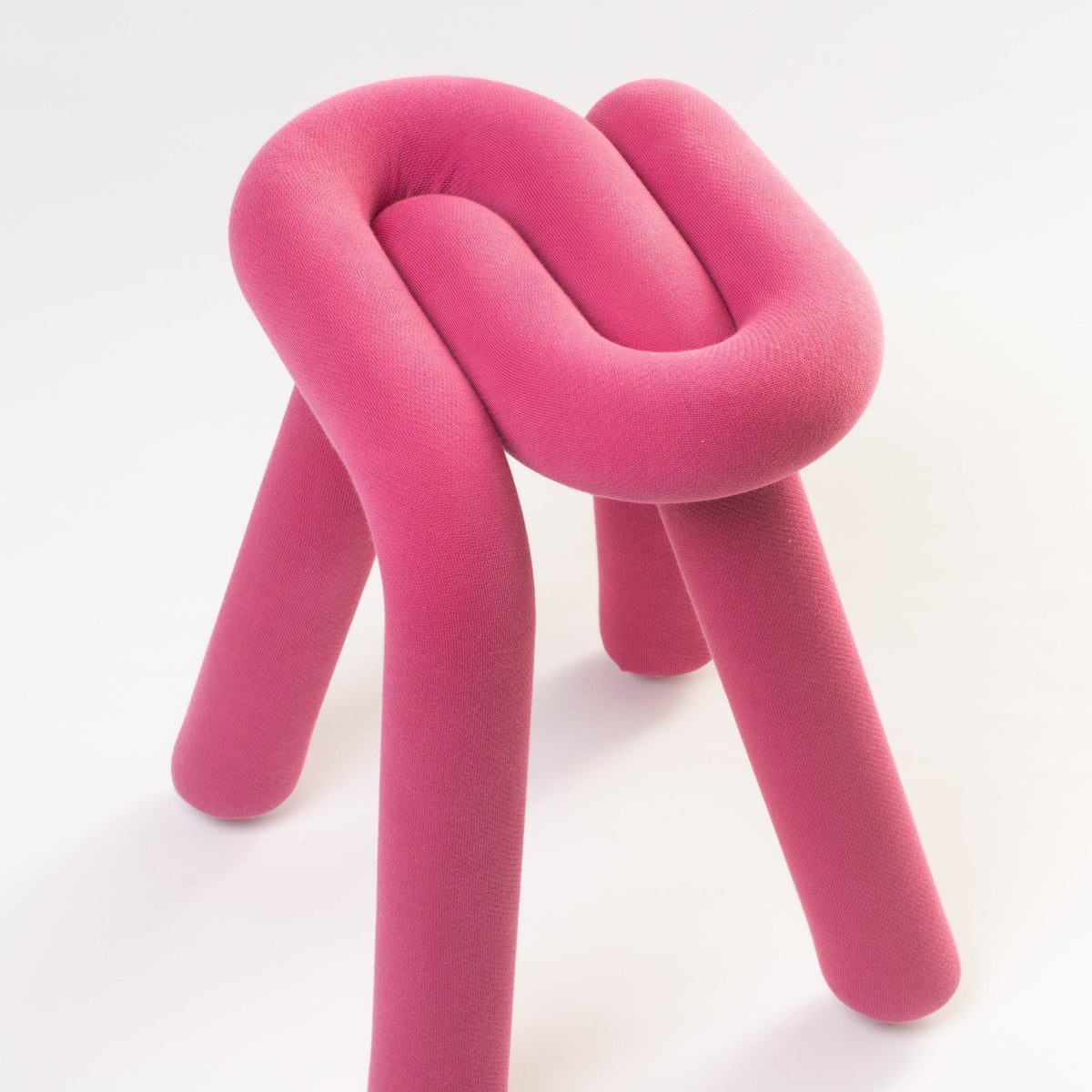 Purple stool by Moustache, with a knotted design and cylindrical legs, against a white background.