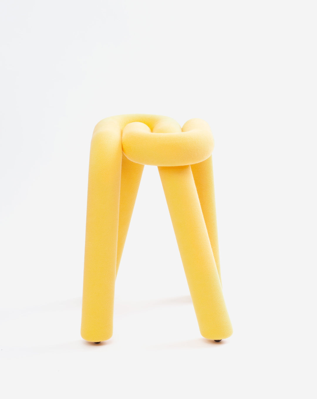 Yellow cylindrical stool by Moustache with a knotted top section, standing on a white background.