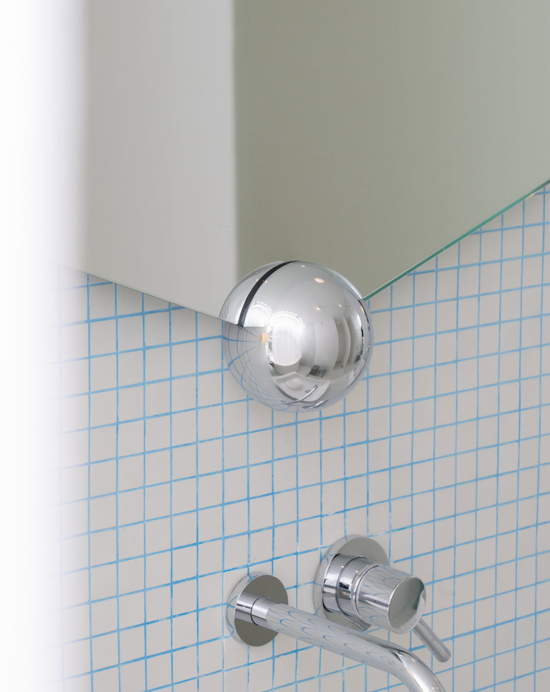 Sphera mirror by Moustache Paris, with a chrome spherical attachment, mounted on tiled wall.