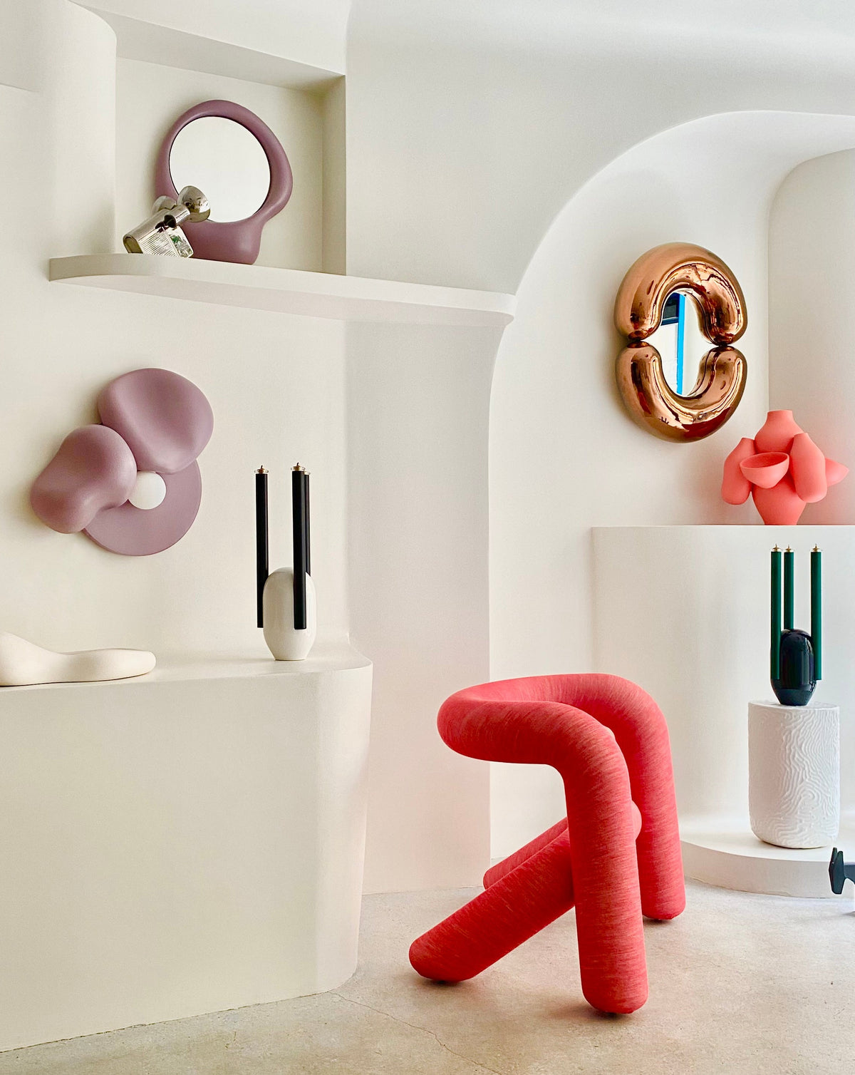 Red, tubular armchair by Kvadrat, displayed in a bright white room with decorative objects.