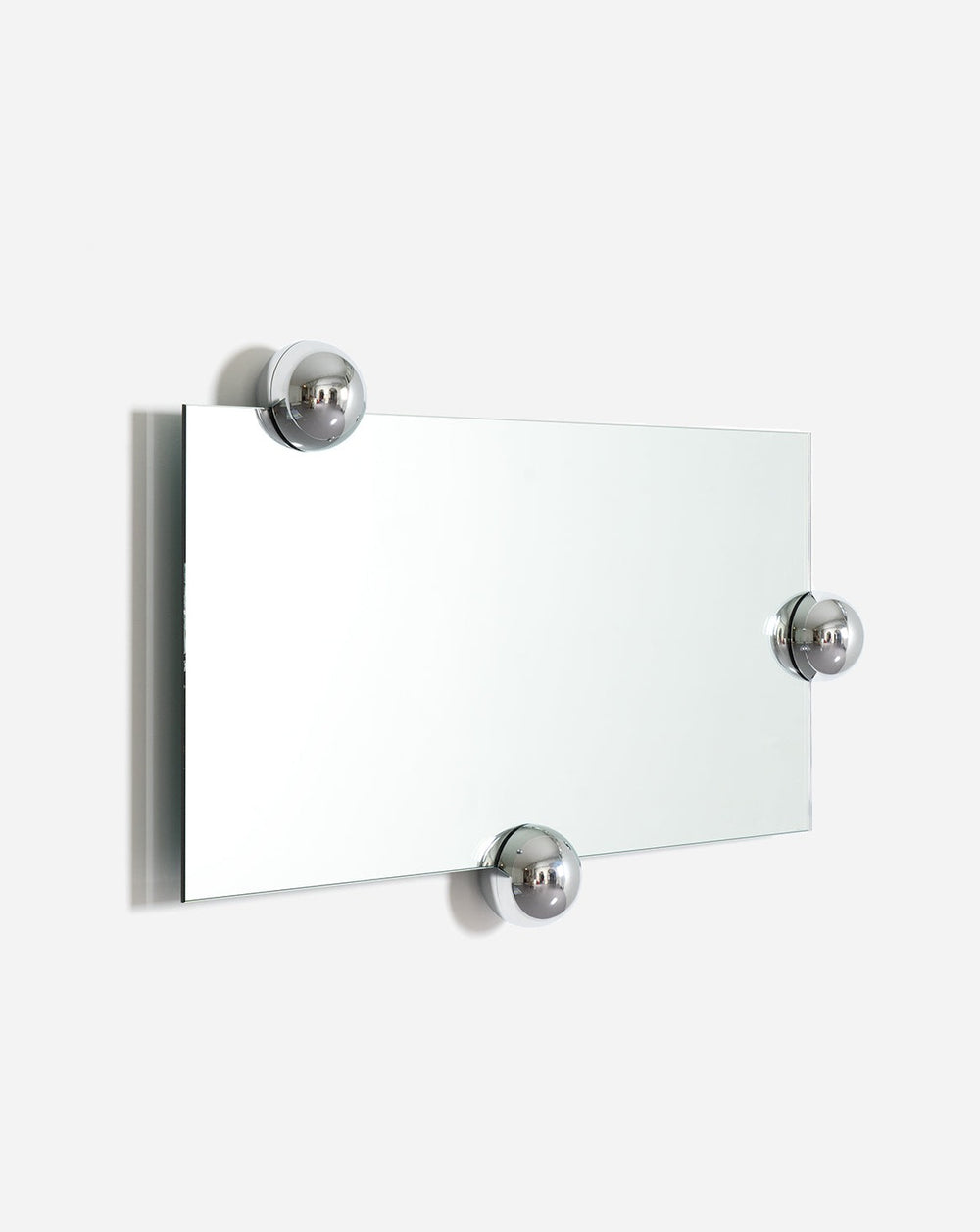 Rectangular wall mirror by Moustache Paris with three spherical chrome fasteners against a white wall.
