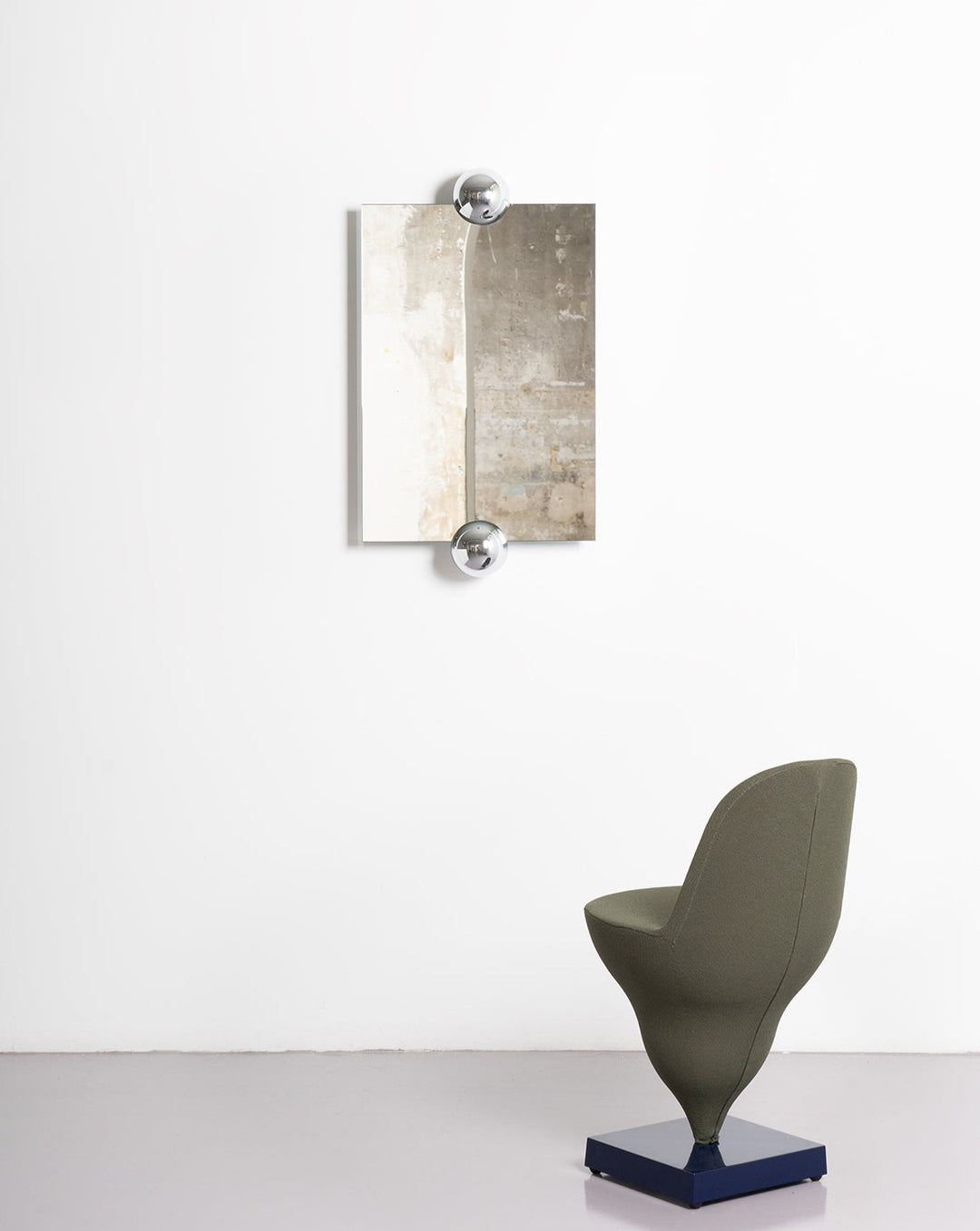 Wall mirror with chrome orbs by Moustache Paris, featuring an asymmetrical two-toned abstract design.
