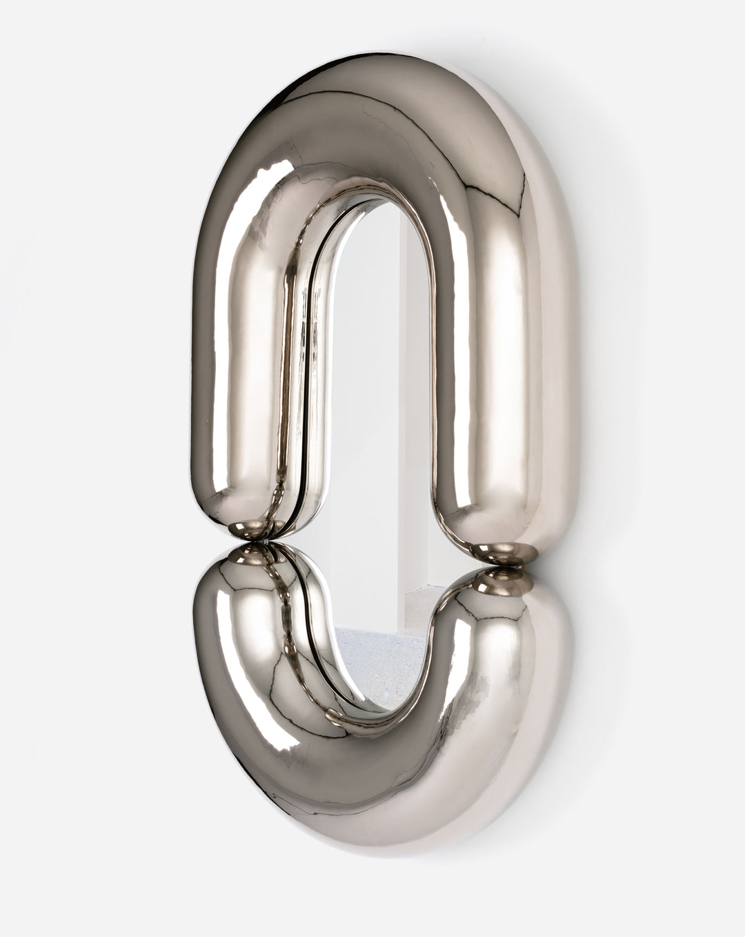 Platinum mirror by Moustache Paris with a double horseshoe shape against a white wall.
