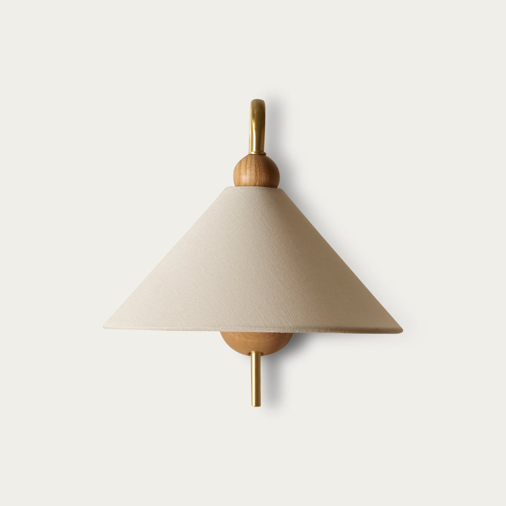 Beige fabric wall sconce by McMullin with wood and gold accents, mounted on a white wall.
