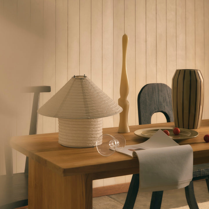 Rice paper table lamp by McMullin with a pleated shade, on a wooden table with decorative items.
