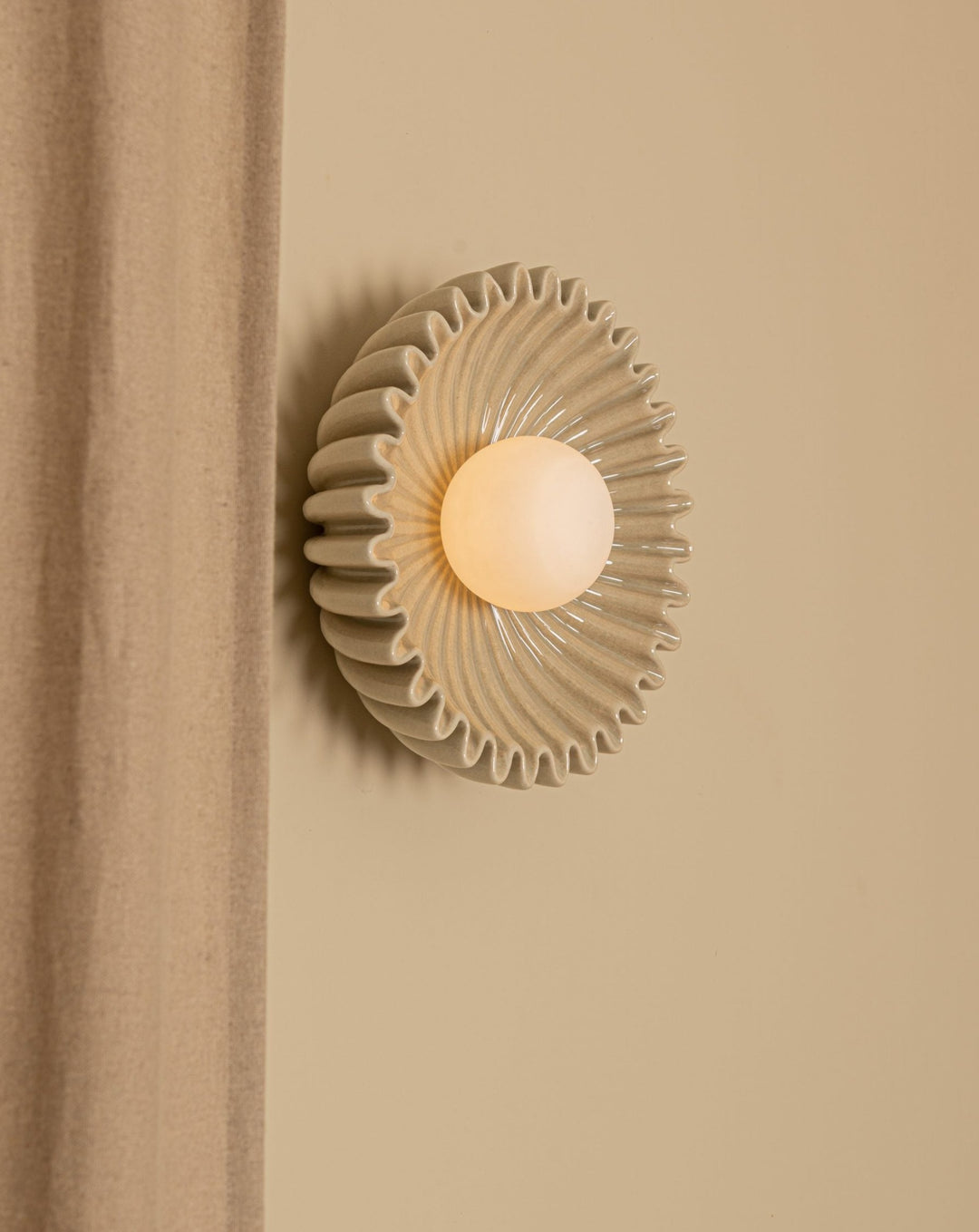 Sea-colored Ostro wall light by Simone and Marcel, with a round bulb and a wavy, ribbed texture.