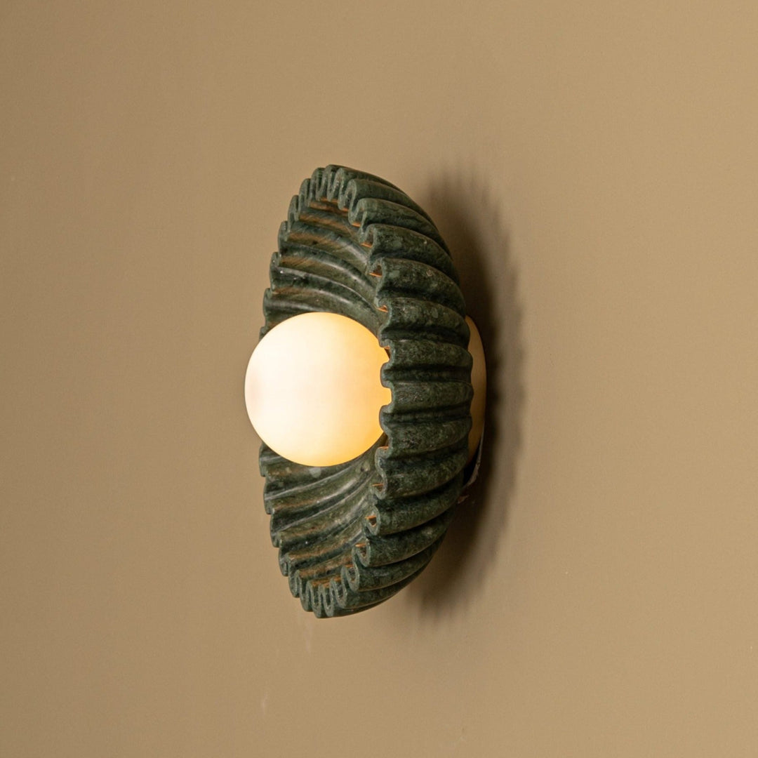 Green marble wall light from Simone and Marcel, featuring a spiral design and glowing bulb.