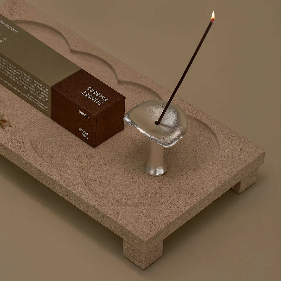 Silver mushroom incense holder by Black Blaze with a burning incense stick, displayed on a decorative tray.
