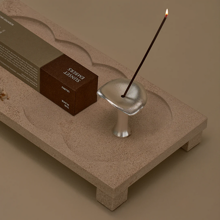 Silver mushroom incense holder by Black Blaze with a burning incense stick, displayed on a decorative tray.
