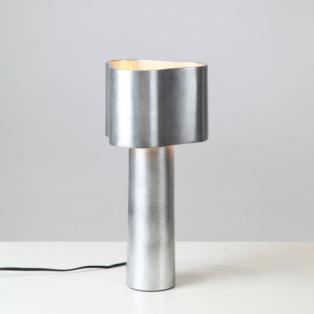 Silver table lamp on a white surface with a gray background