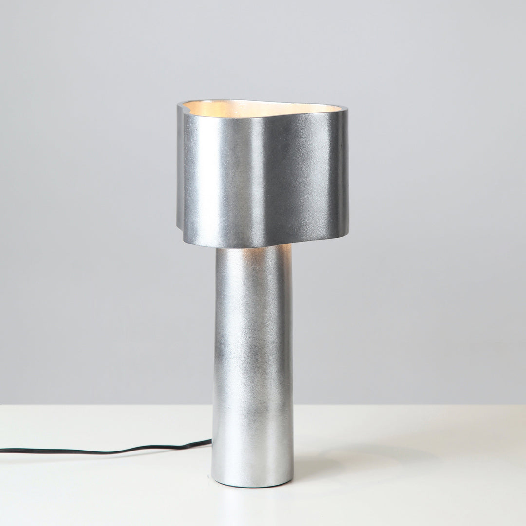 Silver table lamp on a white surface with a gray background